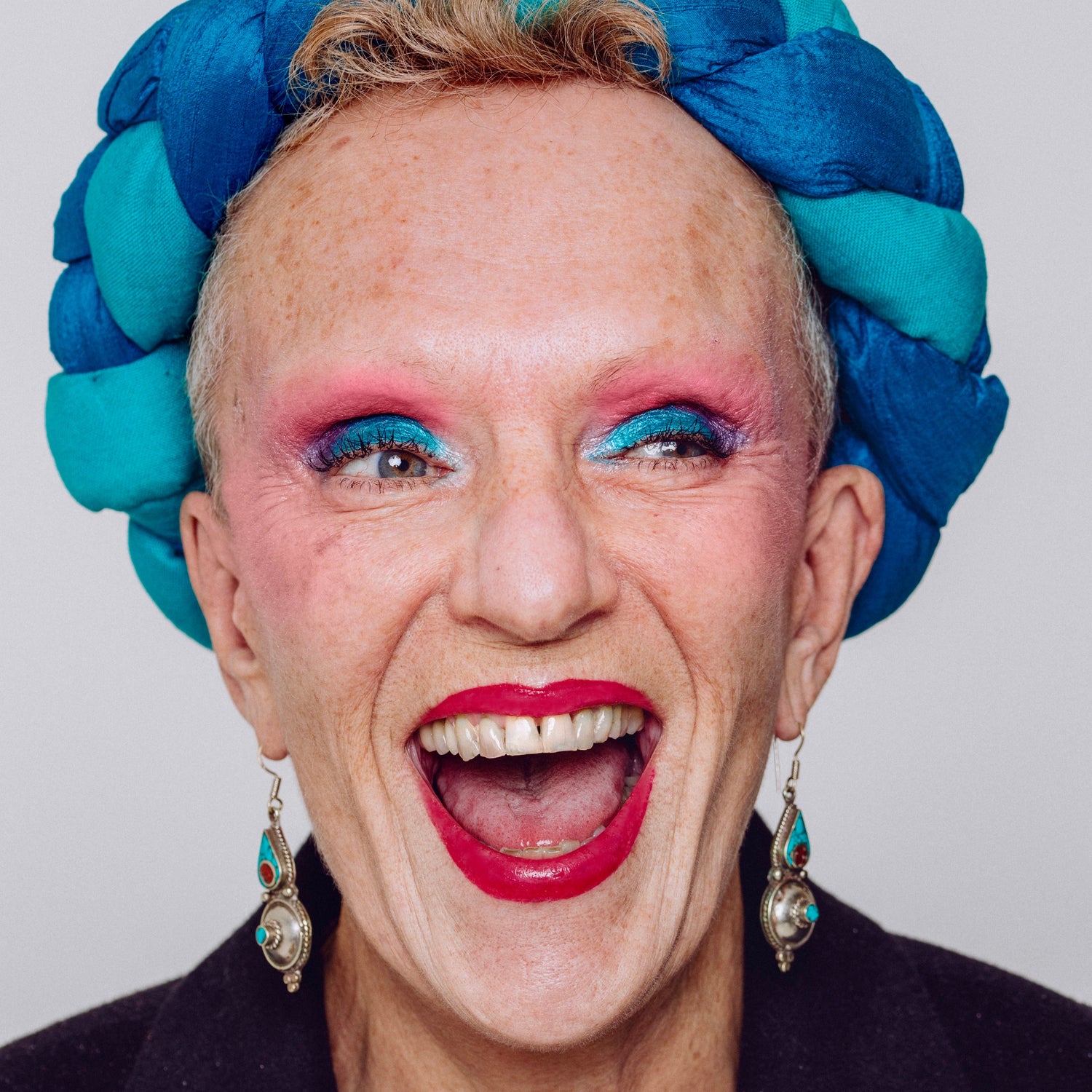 Woman showcasing vibrant makeup from the Makeup Therapy Palette, featuring bold blue and pink hues, perfect for creating unique looks, inspired by therapeutic coloring.