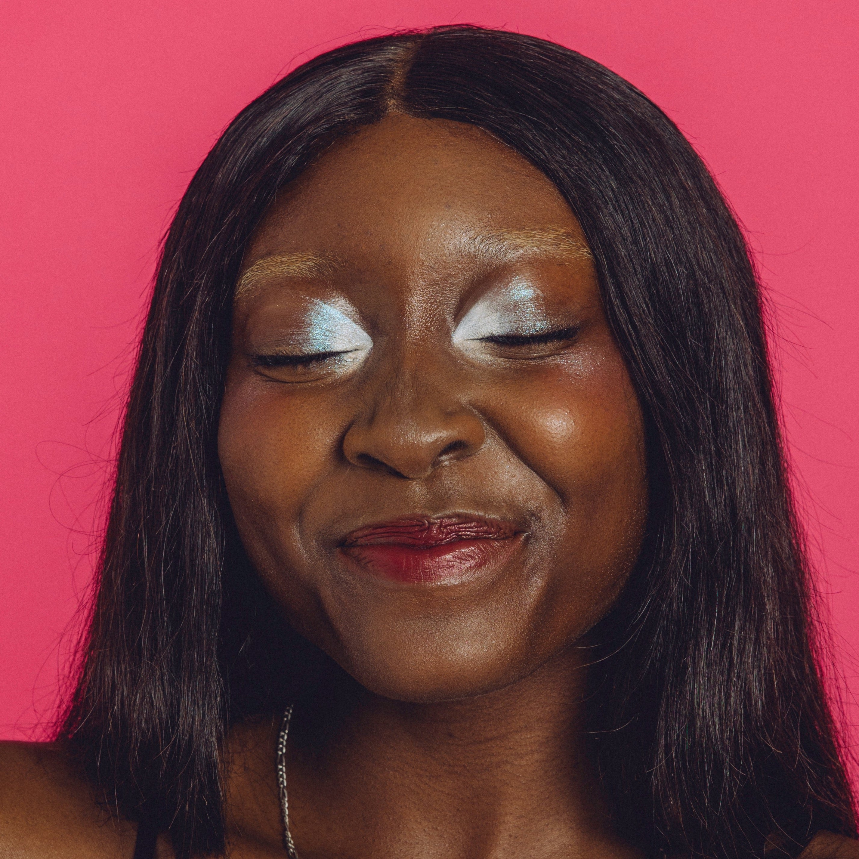 Woman with shimmery silver eyemakeup smiles with her eyes closed.