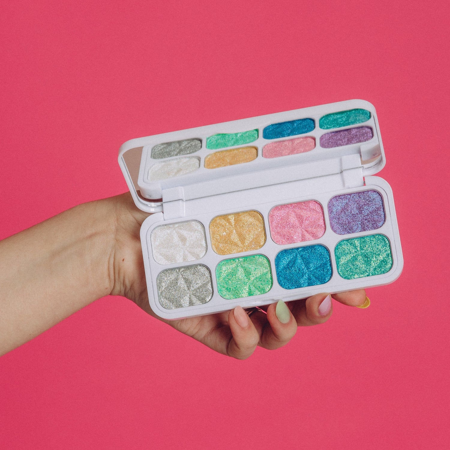 Hand holding the Match Your Mood palette open, showcasing the eight shimmer shades inside in a range of colours.