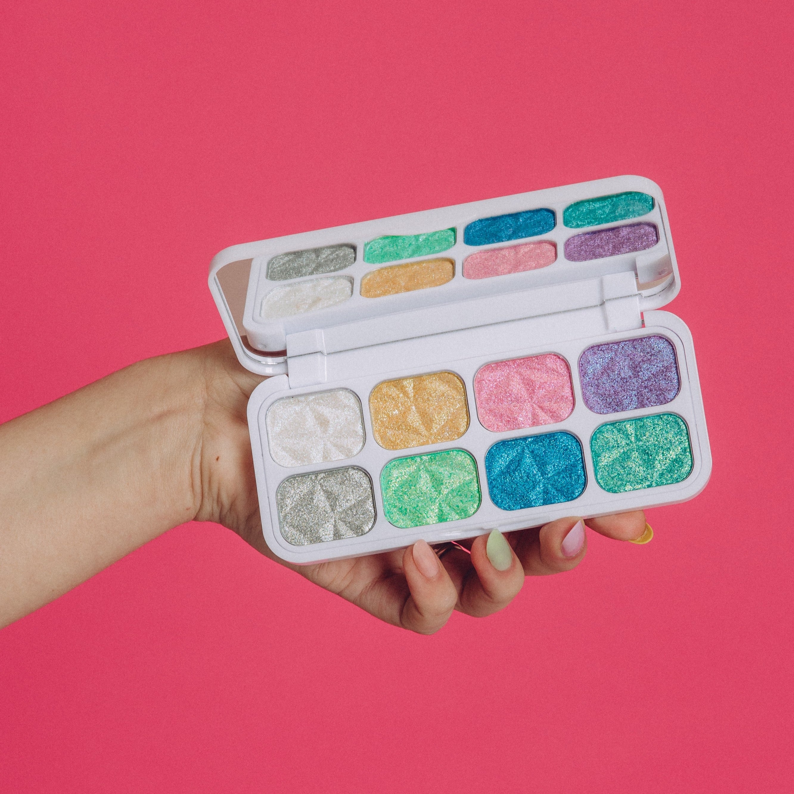 Hand holding the Match Your Mood palette open, showcasing the eight shimmer shades inside in a range of colours.