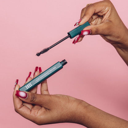 A woman holds the Liquid Confidence™ Mascara, showcasing its easy-hold packaging and brush, designed for applying long, defined lashes effortlessly.