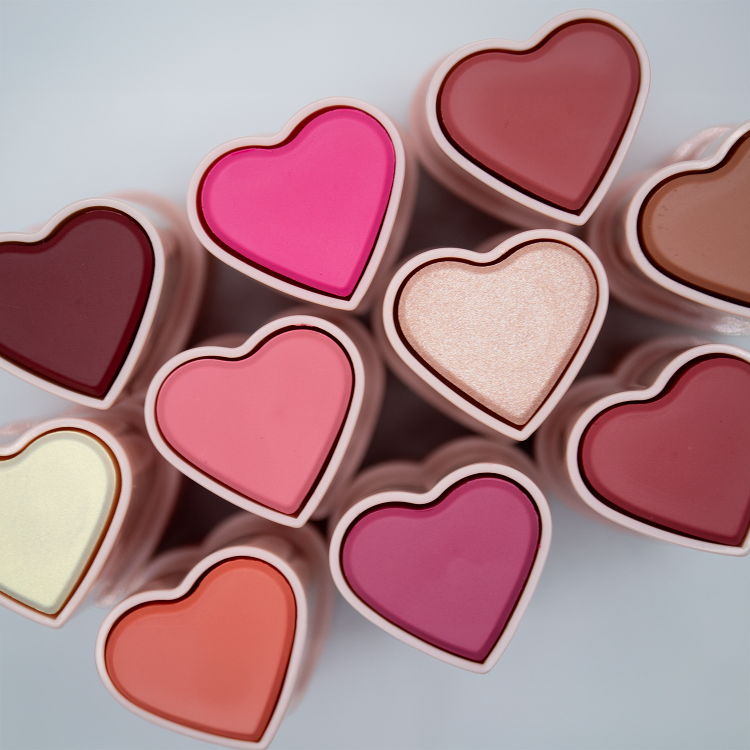 All Dare To Blush heart-shaped blush stick viewed from the top. Colors range from light gold to dark red.